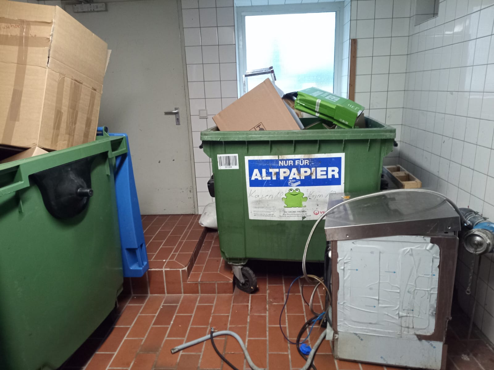 Gefüllter Altpapiercontainer in einem Müllraum